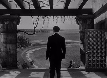 Movie still from “Citizen Kane” (1941), directed by Orson Welles – A black and white photo of a man looking out of a window; Extreme Wide shot, Low angle