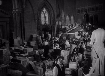 Movie still from “Citizen Kane” (1941), directed by Orson Welles – A group of people in a room with boxes; Extreme Wide shot, High angle
