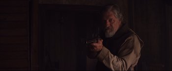 Movie still from “Cowboys & Aliens” (2011), directed by Jon Favreau – An older man holding a gun in a dark room; Medium shot, Over the shoulder angle