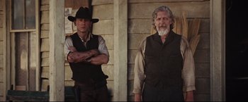 Movie still from “Cowboys & Aliens” (2011), directed by Jon Favreau – Two men standing next to each other in front of a building; Medium shot, Low angle