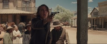 Movie still from “Cowboys & Aliens” (2011), directed by Jon Favreau – A man holding a gun pointed at a man in a cowboy hat; Medium shot, Over the shoulder angle
