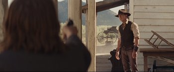 Movie still from “Cowboys & Aliens” (2011), directed by Jon Favreau – A person taking a picture of a man in a cowboy hat; Wide shot, Over the shoulder angle