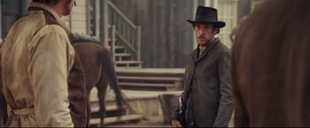 Movie still from “Cowboys & Aliens” (2011), directed by Jon Favreau – A man standing next to a horse on a street; Medium shot, Over the shoulder angle