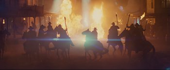 Movie still from “Cowboys & Aliens” (2011), directed by Jon Favreau – A group of people riding horses in front of a fire; Wide shot, Low angle