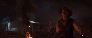 Movie still from “Cowboys & Aliens” (2011), directed by Jon Favreau – A man wearing a cowboy hat standing next to a fire; Medium shot, Low angle