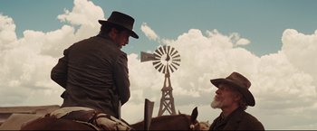 Movie still from “Cowboys & Aliens” (2011), directed by Jon Favreau – Two men are sitting in front of a windmill; Medium shot, Low angle