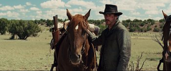 Movie still from “Cowboys & Aliens” (2011), directed by Jon Favreau – A man standing next to a brown horse; Medium shot, Low angle