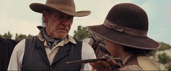 Movie still from “Cowboys & Aliens” (2011), directed by Jon Favreau – A man in a cowboy hat looking at a knife; Close Up shot, Over the shoulder angle