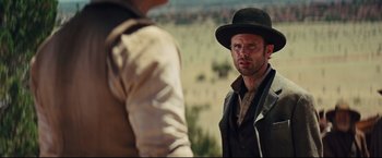 Movie still from “Cowboys & Aliens” (2011), directed by Jon Favreau – A man wearing a black hat standing next to another man; Medium shot, Over the shoulder angle