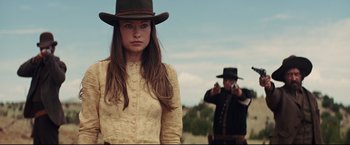 Movie still from “Cowboys & Aliens” (2011), directed by Jon Favreau – A woman in a cowboy hat and a man with a gun; Medium shot, Over the shoulder angle