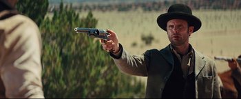 Movie still from “Cowboys & Aliens” (2011), directed by Jon Favreau – A man holding a gun in his right hand; Medium shot, Over the shoulder angle