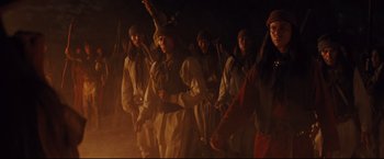 Movie still from “Cowboys & Aliens” (2011), directed by Jon Favreau – A group of people standing in the dark holding flags; Medium shot, Low angle