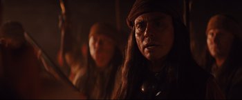 Movie still from “Cowboys & Aliens” (2011), directed by Jon Favreau – A man with long black hair and a brown hat; Close Up shot, Over the shoulder angle