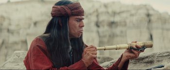 Movie still from “Cowboys & Aliens” (2011), directed by Jon Favreau – A man with long black hair is holding a pipe; Close Up shot, High angle