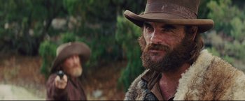 Movie still from “Cowboys & Aliens” (2011), directed by Jon Favreau – A man with a long beard and a hat on; Close Up shot, Over the shoulder angle