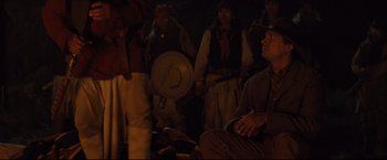 Movie still from “Cowboys & Aliens” (2011), directed by Jon Favreau – A group of people standing in a dark room; Medium shot, Over the shoulder angle