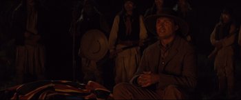 Movie still from “Cowboys & Aliens” (2011), directed by Jon Favreau – A group of people in a dark room; Medium shot, Over the shoulder angle