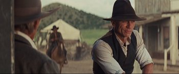 Movie still from “Cowboys & Aliens” (2011), directed by Jon Favreau – A man wearing a hat and a vest is standing in front of a horse; Medium shot, Over the shoulder angle