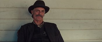 Movie still from “Cowboys & Aliens” (2011), directed by Jon Favreau – An older man wearing a suit and a hat; Close Up shot, Over the shoulder angle