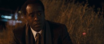 Movie still from “Crash” (2004), directed by Paul Haggis – A man wearing a suit and tie sitting in a dark room; Close Up shot, Over the shoulder angle