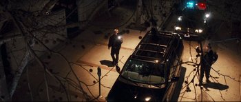 Movie still from “Crash” (2004), directed by Paul Haggis – A man is standing in front of a car at night; Wide shot, Overhead angle