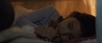 Movie still from “Crash” (2004), directed by Paul Haggis – A young girl laying in bed with a teddy bear; Close Up shot, High angle