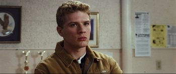 Movie still from “Crash” (2004), directed by Paul Haggis – A young man in a brown jacket looking to his left; Close Up shot, Low angle