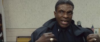 Movie still from “Crash” (2004), directed by Paul Haggis – An older black man is holding his fist up; Close Up shot, Low angle