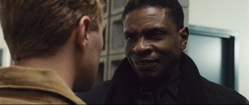 Movie still from “Crash” (2004), directed by Paul Haggis – Two men talking to each other in front of a building; Close Up shot, Over the shoulder angle