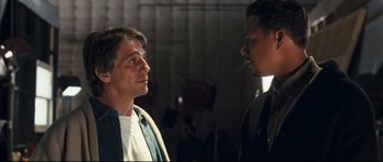 Movie still from “Crash” (2004), directed by Paul Haggis – Two men standing next to each other in front of a building; Close Up shot, Over the shoulder angle