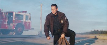 Movie still from “Crash” (2004), directed by Paul Haggis – A man in a brown jacket standing in the street; Medium shot, Low angle