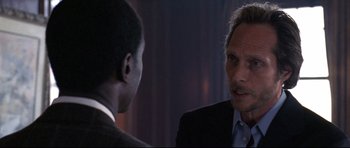 Movie still from “Crash” (2004), directed by Paul Haggis – A man in a suit talking to another man in a business suit; Close Up shot, Over the shoulder angle