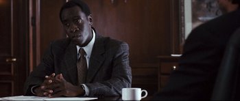 Movie still from “Crash” (2004), directed by Paul Haggis – A man sitting at a table with a cup in front of him; Close Up shot, Over the shoulder angle