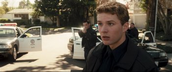 Movie still from “Crash” (2004), directed by Paul Haggis – A man standing in front of a police car; Close Up shot, Over the shoulder angle