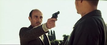 Movie still from “Crash” (2004), directed by Paul Haggis – A man holding a gun pointed at another man; Close Up shot, Low angle