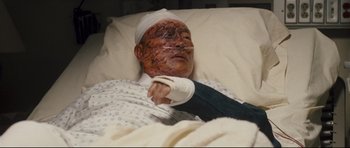 Movie still from “Crash” (2004), directed by Paul Haggis – A man with a bandaged head and arm laying in a hospital bed; Medium shot, Overhead angle