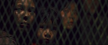 Movie still from “Crash” (2004), directed by Paul Haggis – Two young children behind a fence looking at the camera; Close Up shot, High angle
