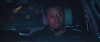 Movie still from “Crash” (2004), directed by Paul Haggis – A man sitting in the back seat of a car at night; Close Up shot, Over the shoulder angle