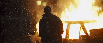 Movie still from “Crash” (2004), directed by Paul Haggis – A man standing in front of a burning car; Medium shot, Over the shoulder angle