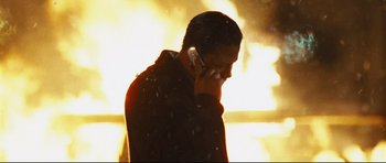 Movie still from “Crash” (2004), directed by Paul Haggis – A man talking on a cell phone while standing in front of a fire; Close Up shot, Low angle