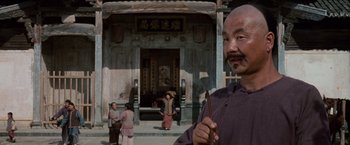 Movie still from “Crouching Tiger, Hidden Dragon” (2000), directed by Ang Lee – An older man standing in front of a building; Medium shot, Low angle