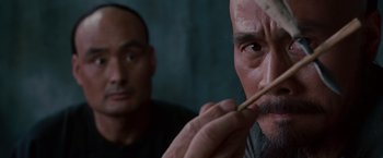 Movie still from “Crouching Tiger, Hidden Dragon” (2000), directed by Ang Lee – A man holding a wooden stick in front of another man; Close Up shot, Low angle