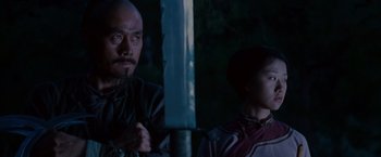 Movie still from “Crouching Tiger, Hidden Dragon” (2000), directed by Ang Lee – A man standing next to a young boy holding a sword; Medium shot, Low angle