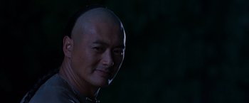 Movie still from “Crouching Tiger, Hidden Dragon” (2000), directed by Ang Lee – A man with a bald head is smiling for the camera; Close Up shot, Over the shoulder angle