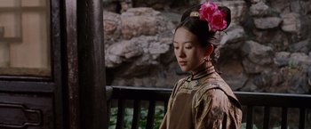 Movie still from “Crouching Tiger, Hidden Dragon” (2000), directed by Ang Lee – A young woman with a pink flower in her hair sitting on a wooden bench; Medium shot, Over the shoulder angle