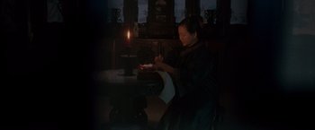 A woman sitting at a dining room table with a candle