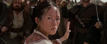 Movie still from “Crouching Tiger, Hidden Dragon” (2000), directed by Ang Lee – A young asian woman in traditional dress with other people in the background; Close Up shot, Over the shoulder angle