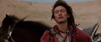 Movie still from “Crouching Tiger, Hidden Dragon” (2000), directed by Ang Lee – A man in a red shirt is standing on a horse; Close Up shot, Low angle