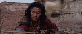Movie still from “Crouching Tiger, Hidden Dragon” (2000), directed by Ang Lee – A man with long black dreadlocks is sitting on the ground; Close Up shot, High angle