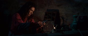 Movie still from “Crouching Tiger, Hidden Dragon” (2000), directed by Ang Lee – A man holding a knife while sitting at a table; Medium shot, Low angle